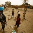Sudanese children stand next to a member of the UN-Afrcian Union mission in Darfur (UNAMID), a mission that expects significant troop cuts under a proposal for strategic review