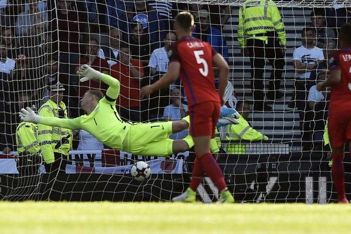 England's goalkeeper Joe Hart (L) dives but cannot reach Scotland's striker Leigh Griffiths' shot on June 10, 2017