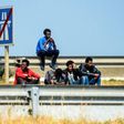 Migrants wait along the ring road leading to the port of Calais, northern France, in June 2017