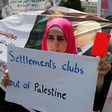 A Palestinian woman holds a red card and a banner opposing the participation in the Israeli league clubs located in Jewish settlements in the occupied West Bank, during a protest in Ramallah May 19, 2015