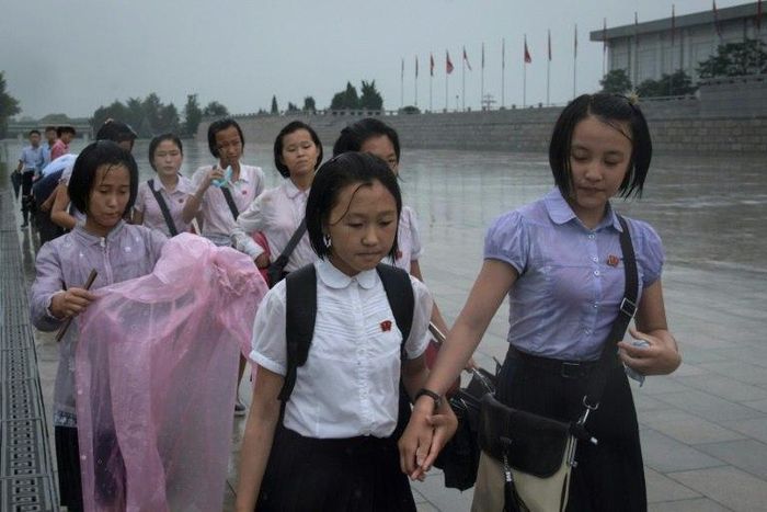 Students walk through the rain to pay their respects to late North Korean leaders Kim Il-Sung and Kim Jong-Il outside Kumsusan Palace as the country marks 'Victory Day' in Pyongyang