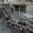 Syrian residents of the rebel-held town of Douma on the outskirts of Damascus break their fast with the "iftar" meal on a heavily damaged street on June 18, 2017, during the Muslim holy month of Ramadan