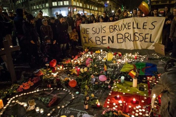 People hold a banner reading in French and Flamish "I AM BRUSSELS" as they gather around tributes for the victims of the Brussels bomb attacks March 22, 2016