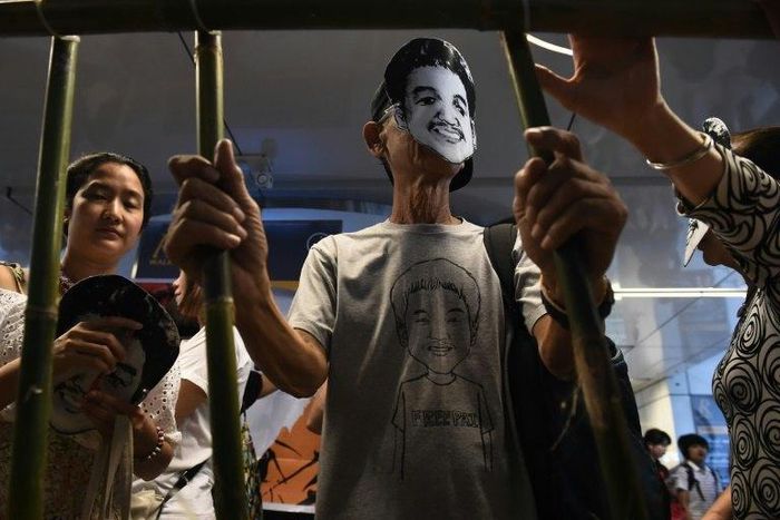 Activists standing behind makeshift bars wearing masks of Thai human rights activist Jatupat “Pai” Boonpattararaksa, who was arrested in early December 2016
