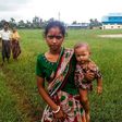 A woman holds a child in her arms as she arrives at Yathae Taung township in Rakhine state after fleeing violence in their home village
