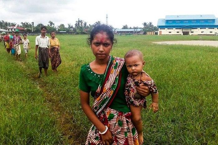 A woman holds a child in her arms as she arrives at Yathae Taung township in Rakhine state after fleeing violence in their home village
