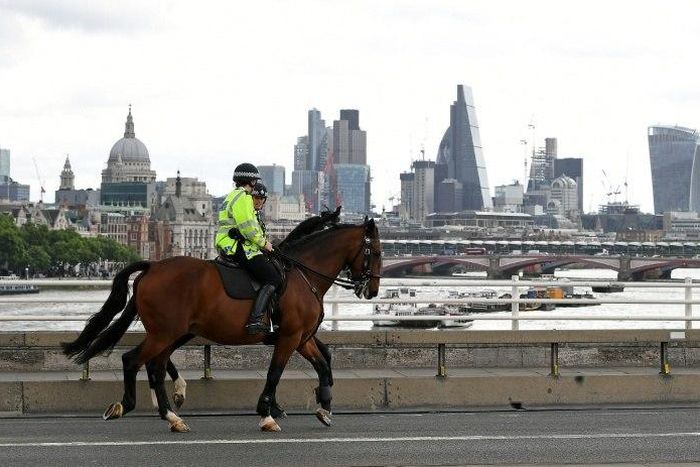 Police on horses ride past a security barrier between the road and the pavement on Waterloo Bridge in London on June 5, 2017, installed in reaction to the recent terror attacks
