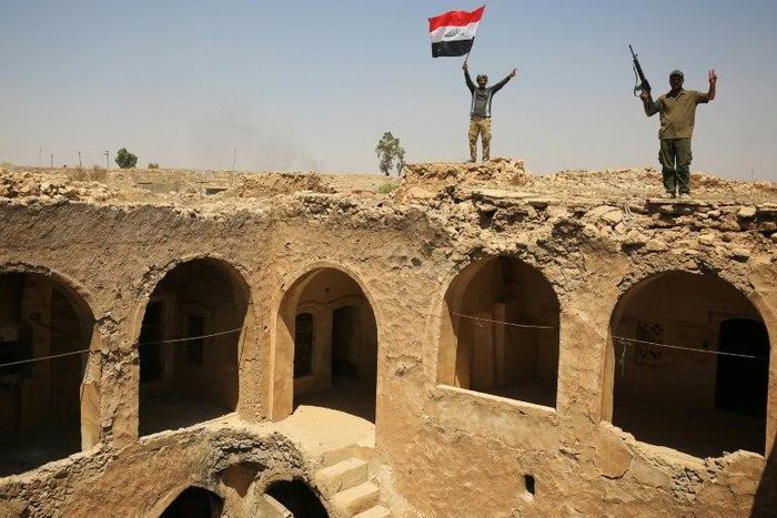 Fighters from the Hashed al-Shaabi paramilitary group raise the Iraqi flag over Tal Afar's historic Ottoman-era citadel after they and Iraqi forces seized it from Islamic State group jihadists
