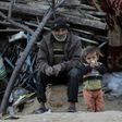 A Palestinian man sits with his son outside their house in an impoverished area in the southern Gaza Strip town of Khan Yunis on February 19, 2017