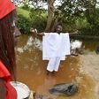 A member of a traditional group stands in the Bodo River with an egg in either hand during the inauguration ceremony of a memorial stone on a site of the former slave route in the Ivorian hamlet of Kanga Gnianze, northwest of Abidjan
