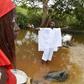 A member of a traditional group stands in the Bodo River with an egg in either hand during the inauguration ceremony of a memorial stone on a site of the former slave route in the Ivorian hamlet of Kanga Gnianze, northwest of Abidjan