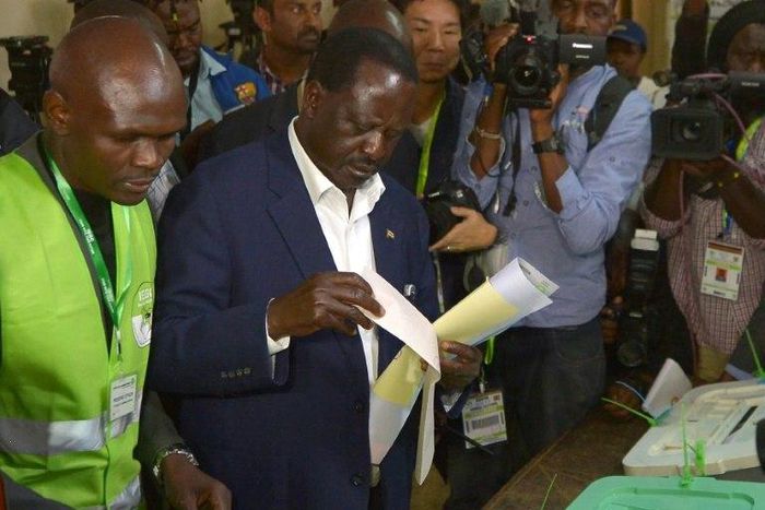 Kenya's opposition alliance, National Super Alliance (NASA) presidential candidate, Raila Odinga prepares to cast his ballots on August 8, 2017 mobbed by a battery of photo journalists at Old-Kibera primary school polling centre, in Nairobi