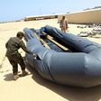 A Libyan naval officer punctures a dinghy used by Illegal migrants, after they were rescued by the Libyan coastguard in the Mediterranean Sea on May 6, 2017