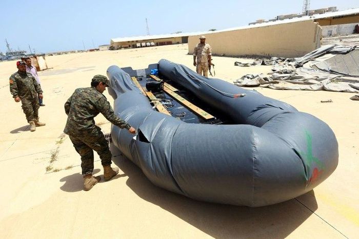 A Libyan naval officer punctures a dinghy used by Illegal migrants, after they were rescued by the Libyan coastguard in the Mediterranean Sea on May 6, 2017