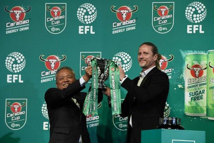 CEO of Carabao Group Sathien Setthasit (L) and former French international footballer Emmanuel Petit raise the EFL Carabao Cup after the first draw for the upcoming season's EFL Cup tournament, at Tawandaeng brewery in Bangkok, on June 16, 2017