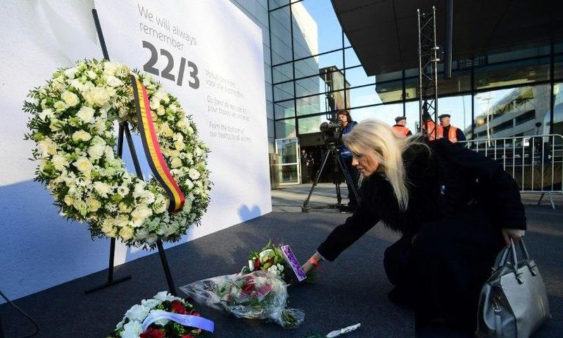 A woman places a bunch of flowers during a memorial at Brussels' international airport in Zaventem