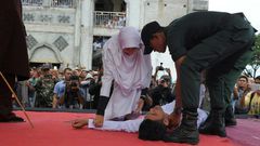 An Acehnese man collapses as he is caned by a religious officer in Banda Aceh on 27th February 2017
