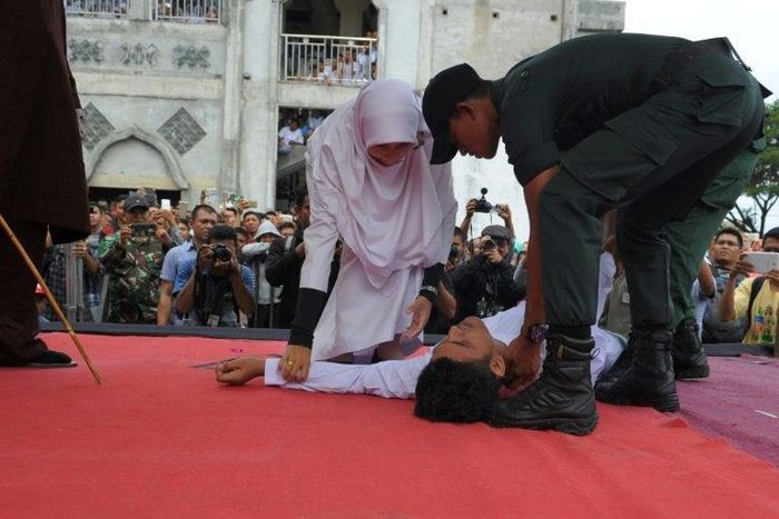 An Acehnese man collapses as he is caned by a religious officer in Banda Aceh on 27th February 2017