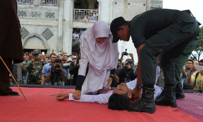 An Acehnese man collapses as he is caned by a religious officer in Banda Aceh on 27th February 2017
