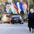 Syrians walk past a giant poster of President Bashar al-Assad and his Russian counterpart Vladimir Putin in the northern Syrian city of Aleppo