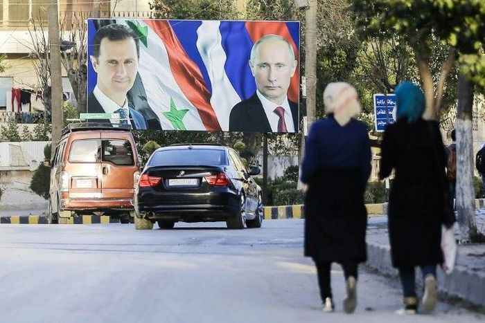 Syrians walk past a giant poster of President Bashar al-Assad and his Russian counterpart Vladimir Putin in the northern Syrian city of Aleppo