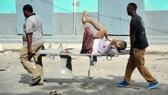 Residents carry an injured man wounded during a complex car bomb attack targeting a Mogadishu hotel on January 25, 2017