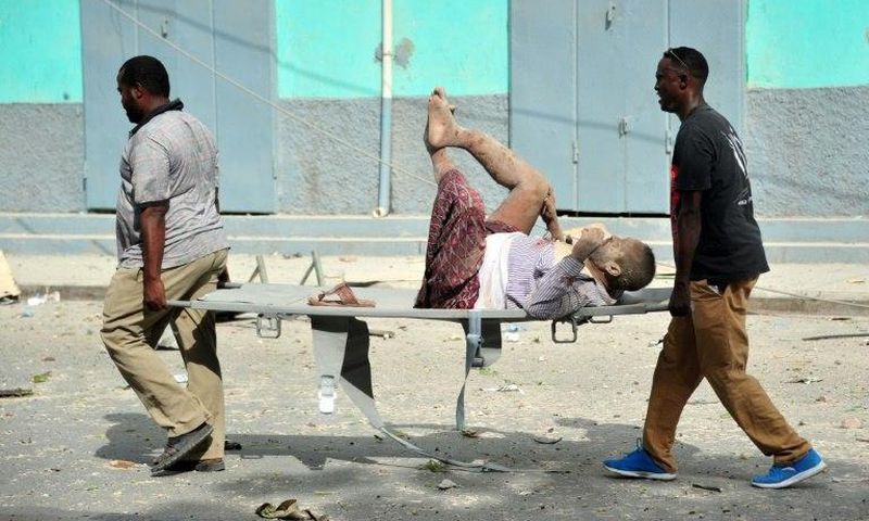 Residents carry an injured man wounded during a complex car bomb attack targeting a Mogadishu hotel on January 25, 2017