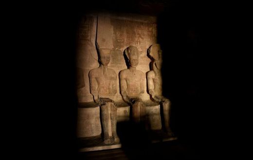 A picture taken on October 22, 2016, shows a ray of light illuminating the statue of Ramses II inside the temple of Abu Simbel in Egypt