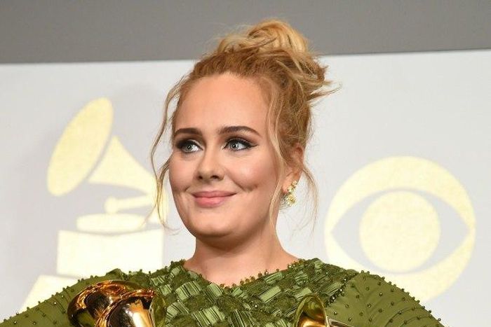 Adele poses in the press room with her five trophies, including the top two Grammys of Album and Record of the Year for her blockbuster hit "Hello" and the album "25"