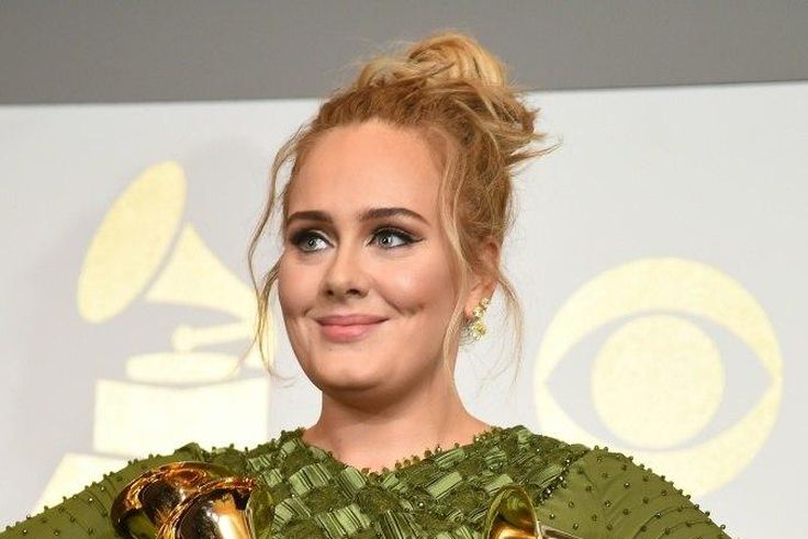 Adele poses in the press room with her five trophies, including the top two Grammys of Album and Record of the Year for her blockbuster hit "Hello" and the album "25"