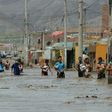 Residents of the town of Huarmey, 300 km north of Lima, wade through muddy water in the street after a flash flood hit the area the night before