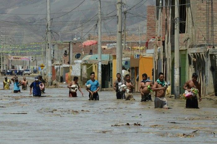 Residents of the town of Huarmey, 300 km north of Lima, wade through muddy water in the street after a flash flood hit the area the night before