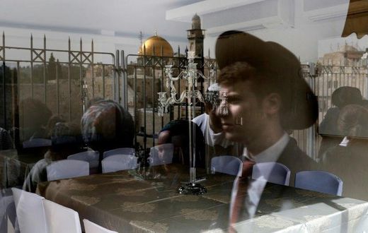 A picture taken through the window of a restaurant shows a reflection of Jews taking part in the Passover priestly blessing at Jerusalem's Western Wall on April 13, 2017, with the Dome of the Rock seen in the background