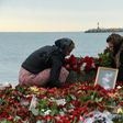 People lay flowers next to a portrait at a makeshift memorial in Sochi, on December 27, 2016 after a military plane carrying 92 people, including dozens of members of the Red Army Choir, crashed in the Black Sea