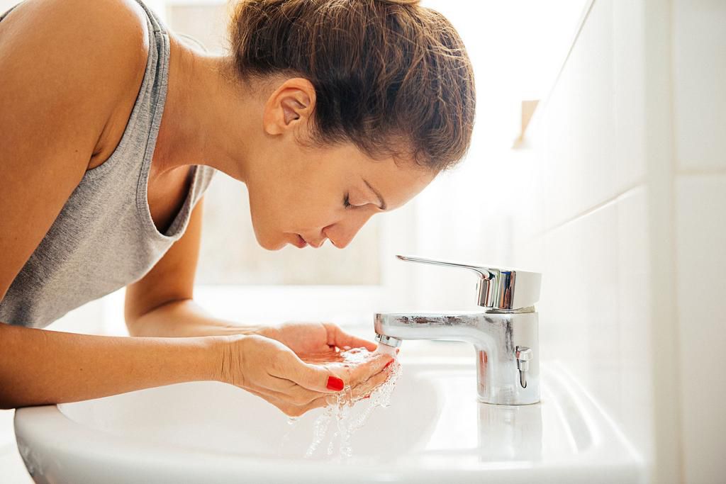 Young cheerful woman having morning hygiene in bathroom