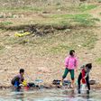 A North Korean soldier reads a book near women washing clothes in the Yalu border river on April 16, 2017