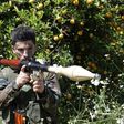 A Hezbollah fighter stands at attention in an orange field near the town of Naqura on the Lebanese-Israeli border on April 20, 2017