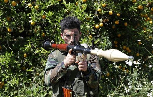 A Hezbollah fighter stands at attention in an orange field near the town of Naqura on the Lebanese-Israeli border on April 20, 2017