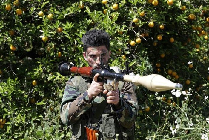 A Hezbollah fighter stands at attention in an orange field near the town of Naqura on the Lebanese-Israeli border on April 20, 2017