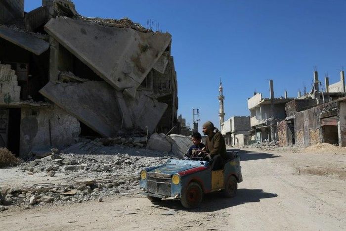 A Syrian man drives a home-made toy car through Beit Naim, a town in the Eastern Ghouta bastion near Damascus, on March 7, 2017
