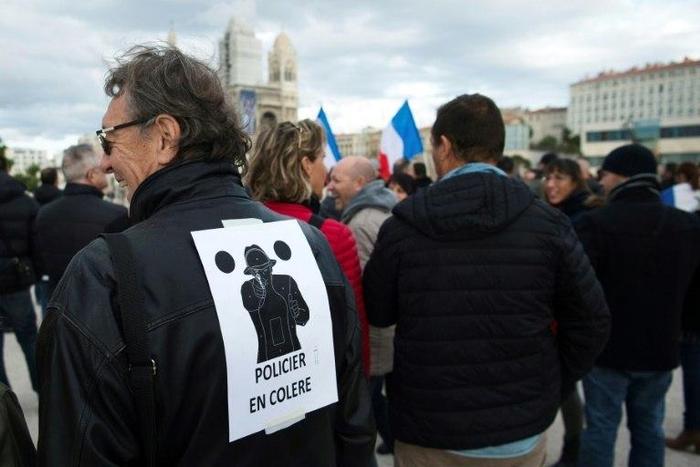 A man wears a poster on his back which translates as "angry policemen" during a demonstration over mounting attacks on officers and to call for reinforcements and more resources, on December 3, 2016 in Marseille, France