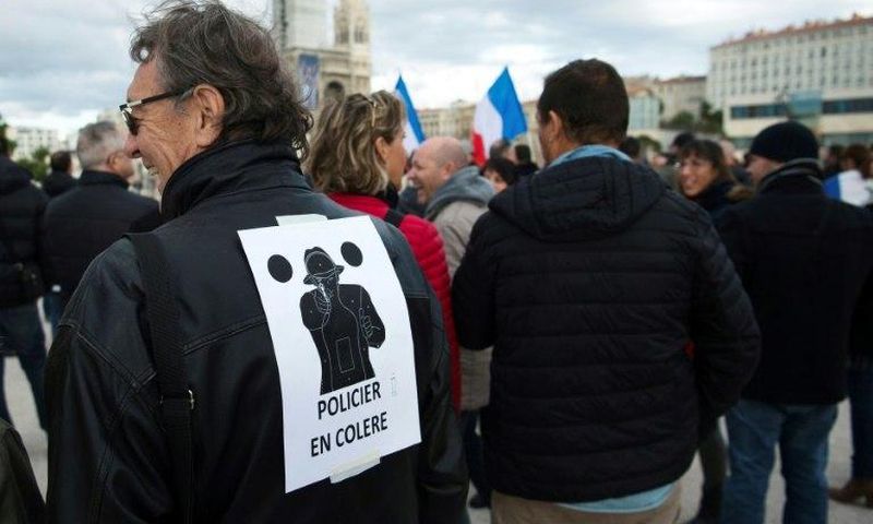 A man wears a poster on his back which translates as "angry policemen" during a demonstration over mounting attacks on officers and to call for reinforcements and more resources, on December 3, 2016 in Marseille, France