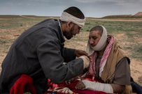 Abdulrahman Salam aids his injured father, Salam Abid, at a screening point for those fleeing the last village controlled by ISIS. They said 20 members of their family had been killed by a coalition airstrike.CreditIvor Prickett for The New York Times