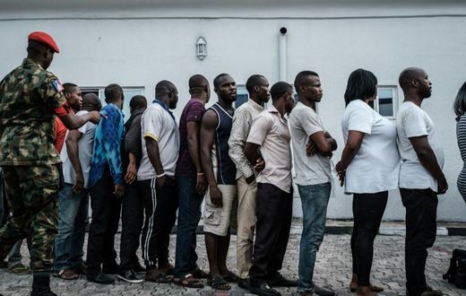 Suspects who were arrested by Nigerian Army personnel on election day in connection with various alleged electoral offenses, including stealing a carton of presidential ballot papers, stand in line to be handed over to police in Port Harcourt