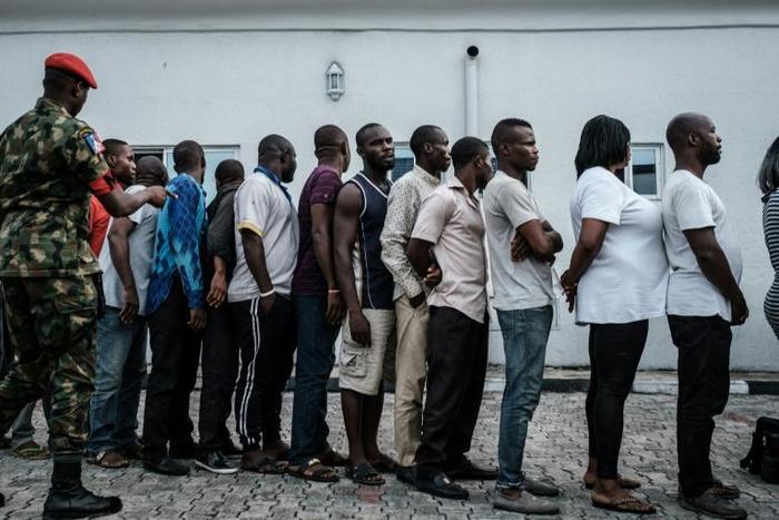 Suspects who were arrested by Nigerian Army personnel on election day in connection with various alleged electoral offenses, including stealing a carton of presidential ballot papers, stand in line to be handed over to police in Port Harcourt