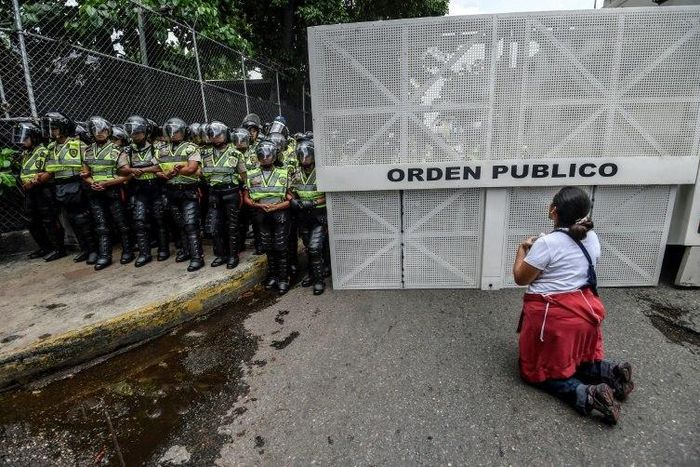 A woman kneels during a silent march by the opposition in a show of condemnation of the government of Venezuelan President Nicolas Maduro, in Caracas