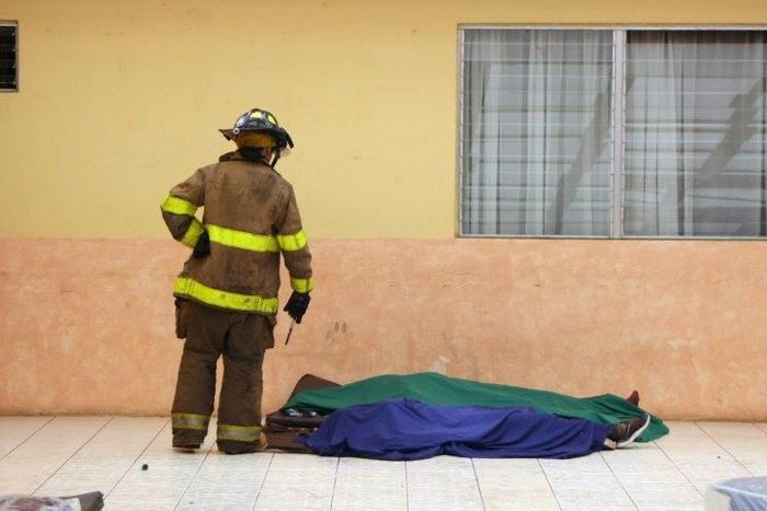 A firefighter looks at two victims at a government-run children's shelter in San Jose Pinula after fire swept the building east of Guatemala City