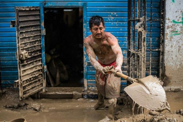 Residents of a populous district of Lima remove mud, debris and water left by a flash flood from their homes, on March 19, 2017