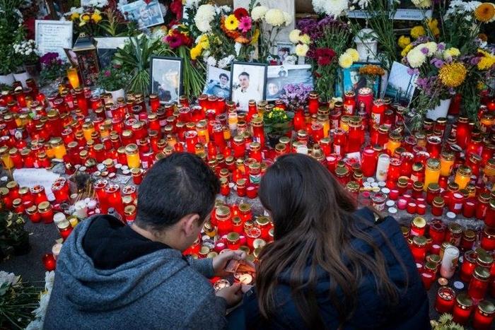A couple lights candles at the end of a march in the memory of the 64 people who were killed one year ago when Colectiv club caught fire during a rock concert, on October 30, 2016 in Bucharest
