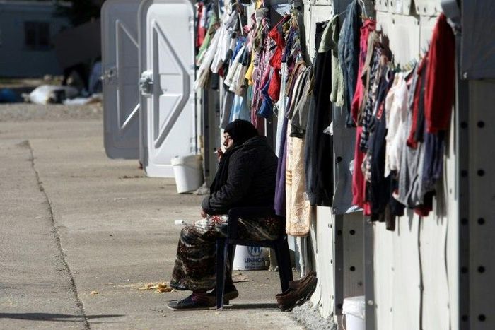 A woman smokes a cigarette at a refugee camp in Thessaloniki